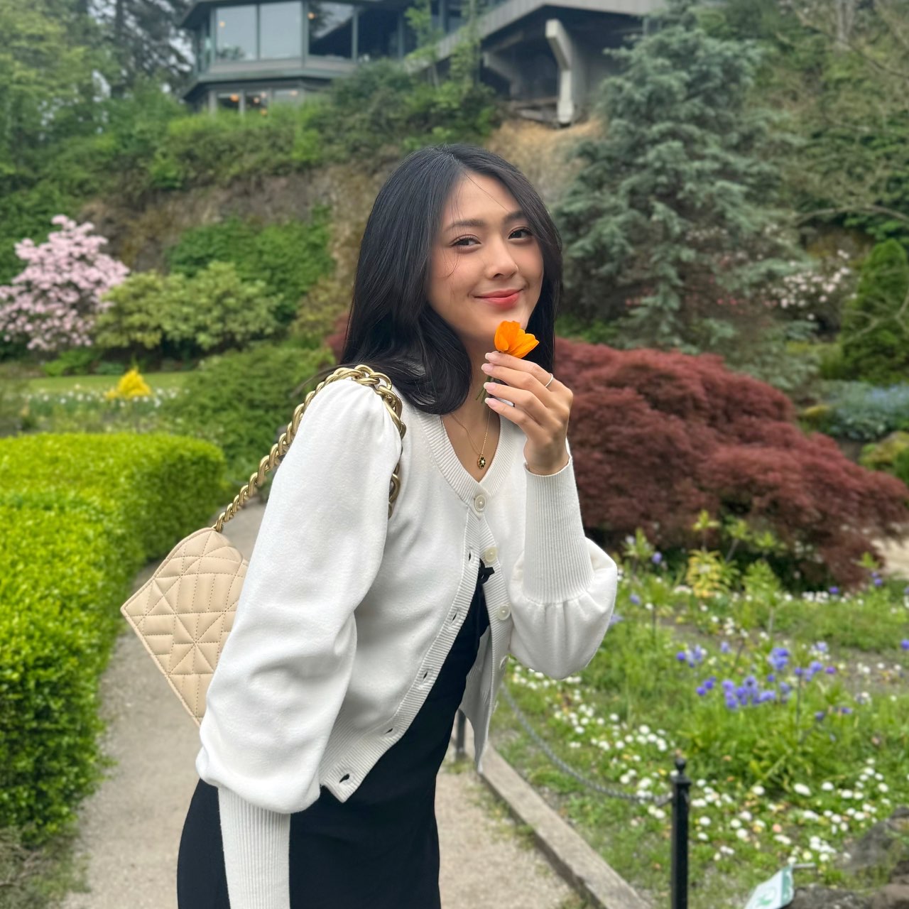 Candice smiling with an orange poppy in a spring garden